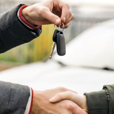 2 hombres haciendo un trato. Uno pasa las llaves del vehículo al otro. Logo del paquete de Individual